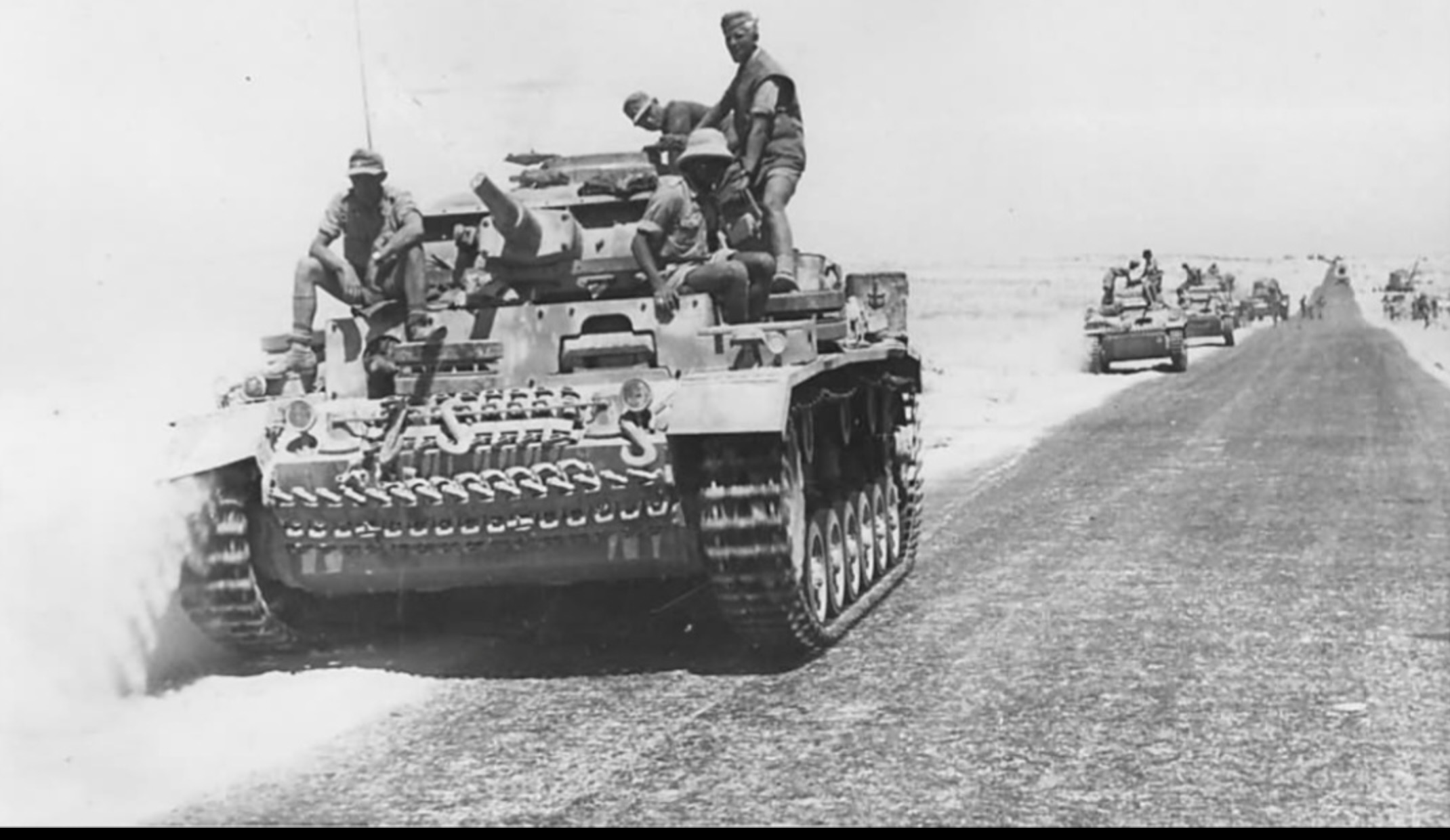 A Panzer III tank followed by German armored vehicles heading to battle.